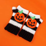 Black and white striped crochet hand warmers with halloween inspired Jack O' Lantern faces. VelvetVolcano Pumpkin Stripe Fingerless Gloves