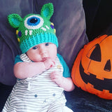 A baby wearing a VelvetVolcano crochet cyclops kitty beanie