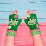 Emerald green crochet hand warmers with pastel frog, strawberry and daisy design and pastel green cuffs with pink frill at the top. Froggy Fingerless Gloves by VelvetVolcano