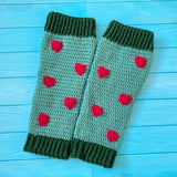 Sage green crochet leg warmers with forest green cuffs and burgundy heart pattern by VelvetVolcano. Background is turquoise wood.