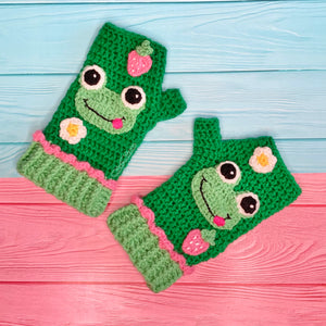 Emerald green crochet hand warmers with pastel frog, strawberry and daisy design and pastel green cuffs with pink frill at the top. Froggy Fingerless Gloves by VelvetVolcano
