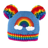 A dolphin blue crocheted beanie with a rainbow and cloud motif on the front of the hat, 2 rainbow Pom Poms positioned like bear ears and a rainbow striped ribbed brim by VelvetVolcano