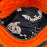 The black and white halloween print lining of the VelvetVolcano Creature Feature Bum Bag. The fabric features pumpkins, spider webs, bats and stars.