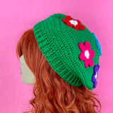 Grass green crochet beret with daisy design, each flower a different rainbow colour. Bright Rainbow Daisy Daze Beret by VelvetVolcano