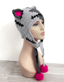 Half light grey, half darker grey Frankenstein's Monster inspired crochet cat ear, ear flap beanie with cerise pink inner ears and pom poms. Custom Colour FrankenKitty Ear Flap Beanie by VelvetVolcano