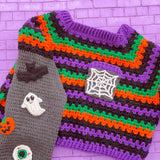 Black, purple, green and orange striped crochet jumper / sweater with spider web chest pocket and grey sleeves with bat, pumpkin, ghost, eyeball, spider and spider web applique designs. Cropped Spooky Season Sweater / Jumper by VelvetVolcano