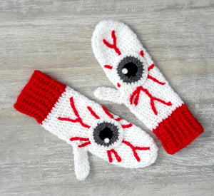 White crochet mittens with red cuffs and eyeball design including red blood vessels. Eye See You Mittens by VelvetVolcano