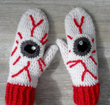 White crochet mittens with red cuffs and eyeball design including red blood vessels. Eye See You Mittens by VelvetVolcano