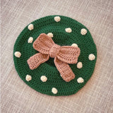 Forest green crochet beret with beige polka dots and a fudge brown bow in the centre by VelvetVolcano