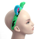 Half neon green and half turquoise cat ear headband with each ear being the opposite colour to the side it is on. The inner ears are neon pink and there are black embroidered stitch marks to look like the cat has been pieced together. FrankenKitty Crochet Headband by VelvetVolcano