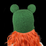 Dark forest green crochet earflap hat with frog eyes at the top of the hat and pom poms at the ends of the earflap ties. Froggy Earflap Beanie by VelvetVolcano