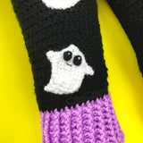 Black crochet leg warmers with a column of white ghosts with cute smiley faces and lilac ribbed cuffs. - VelvetVolcano Acrylic Crochet Spooky Ghost Leg Warmers