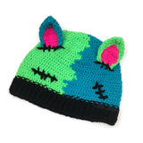 Half neon green, half turquoise crochet beanie with cat ears (which are neon pink inside) and a black ribbed brim, designed to look like a Frankenstein's Monster Kitty. Custom Colour FrankenKitty Beanie by VelvetVolcano