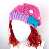 Bubblegum Pink crochet slouchy beanie with White polka dot pattern, Lilac contrast ribbed bottom section with a Turquoise bow positioned to the side on the ribbed section. Polka Dot Bow Slouchy Beanie (Custom Colour) by VelvetVolcano