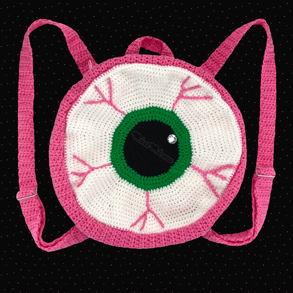 Crochet Circular Eyeball Backpack in white with an emerald green iris and bubblegum pink main part of the bag. straps and blood vessel design. Pastel Eye See You Backpack by VelvetVolcano