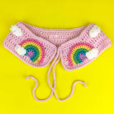 Baby Pink crochet Peter Pan style detachable collar with tie closure, repeating white cloud pattern and pastel rainbow with a cloud at the end motif of each lapel. Pastel Rainbow Cloud Collar (Baby Pink) by VelvetVolcano