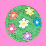 Pastel green crochet beret with 6 daisy appliques, a standard white and yellow daisy in the centre with Peach, Pastel Yellow, Turquoise, Lilac and Bubblegum Pink daisies (all with white centres) in a circle around the centre daisy. Multicolour Kawaii Pastel Rainbow Daisy Daze Beret by VelvetVolcano