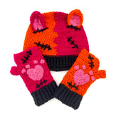 Half orange, half hot pink crochet beanie with cat ears and a black ribbed brim, designed to look like a Frankenstein's Monster Kitty with matching fingerless gloves that have bubblegum pink heart shaped cat paws. Custom Colour FrankenKitty Beanie by VelvetVolcano