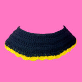 The back of a VelvetVolcano Sunflower Collar, which is a crocheted black Peter Pan collar with a yellow scallop trim.