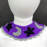 VelvetVolcano Witchy Collar, a violet Peter Pan style crochet detachable collar with black pentagrams, grey moons and black stars and a grey scallop trim around the bottom edge.