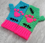 Turquoise and Neon Green Crochet Hand Warmers with Neon Pink cuffs, Black embroidered stitch patterns and neon pink heart shaped paws. FrankenKitty Fingerless Gloves by VelvetVolcano