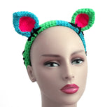 Half neon green and half turquoise cat ear headband with each ear being the opposite colour to the side it is on. The inner ears are neon pink and there are black embroidered stitch marks to look like the cat has been pieced together. FrankenKitty Crochet Headband by VelvetVolcano