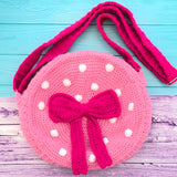 Bubblegum pink circular shaped crochet shoulder bag with white polka dot pattern, hot pink strap and hot pink bow with tails in the centre of the bag. Polka Dot Bow Bag (Custom Colour) by VelvetVolcano