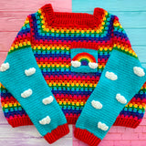 Bright Rainbow striped crocheted cropped jumper with Turquoise sleeves with White cloud applique pattern and a chest pocket with a rainbow and cloud motif by VelvetVolcano