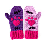A set of crochet mittens with a Frankenstein's Monster & Zombie Cat inspired design, with one lilac mitten, one violet mitten, black embroidered stitch details and hot pink heart shaped paws and cuffs - NecroKitty Mittens by VelvetVolcano