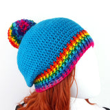 Blue slouchy crochet bobble hat with rainbow pom pom and rainbow striped brim by VelvetVolcano